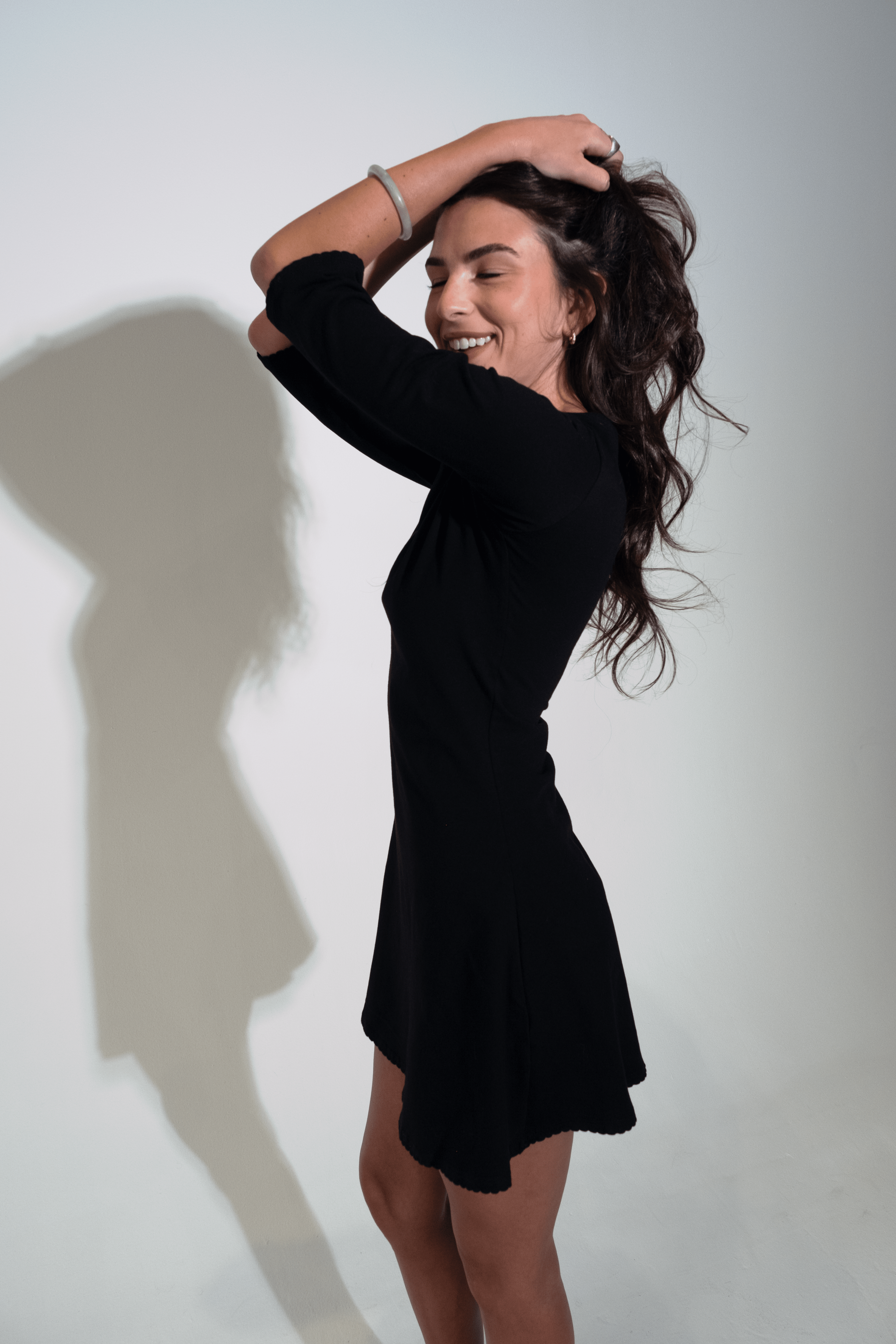 Woman in a black dress posing against a white background