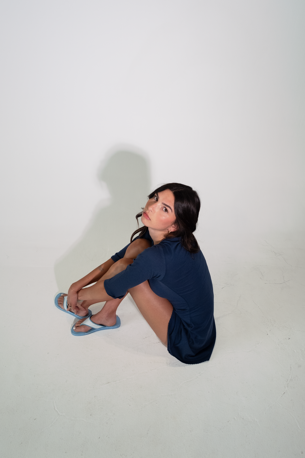 Person sitting on a white floor with a plain white background
