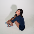 Person sitting on a white floor with a plain white background