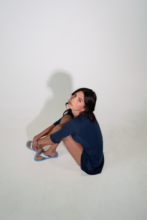 Person sitting on a white floor with a plain white background