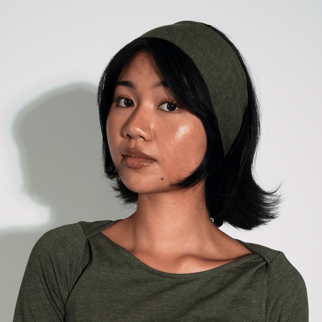 Woman wearing a green dress and headscarf against a white background