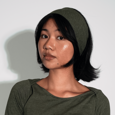 Woman wearing a green dress and headscarf against a white background