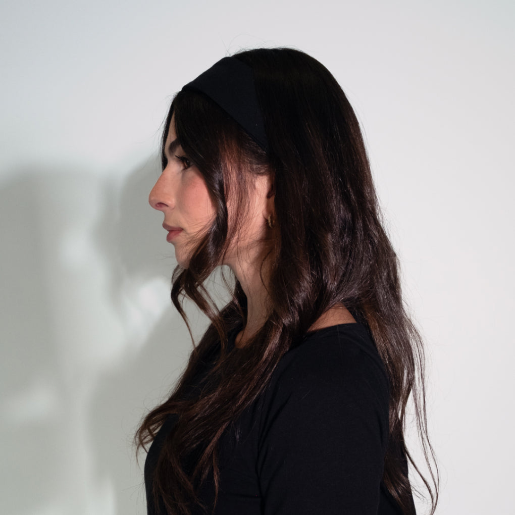 Woman with long dark hair wearing a black top against a white background