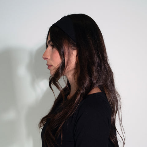 Woman with long dark hair wearing a black top against a white background