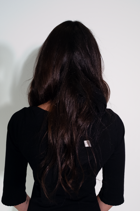 Person wearing a black dress with a visible brand tag against a white background