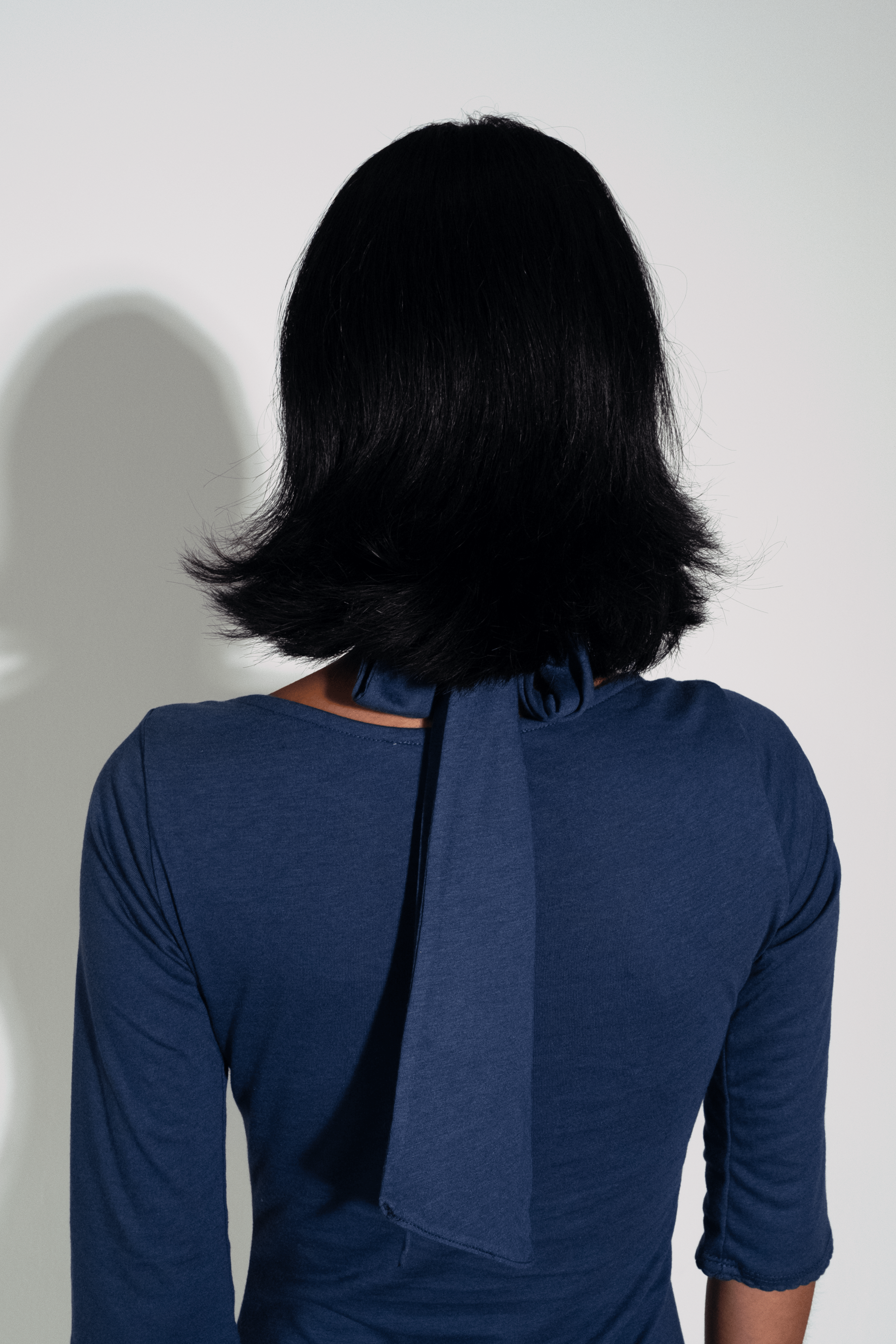 Person wearing a blue dress with a bow detail on a white background