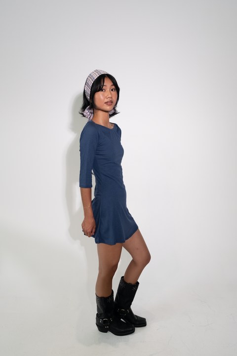 Woman wearing a blue dress and black boots against a white background