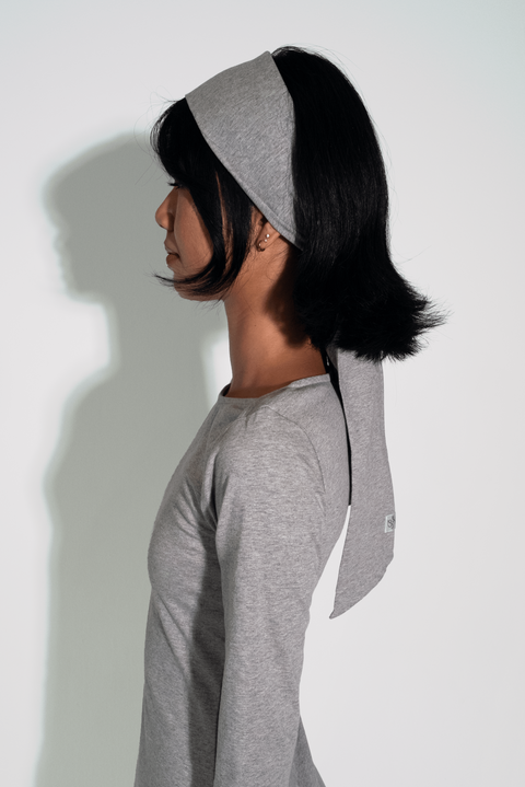 Person wearing a gray long-sleeve shirt and headband against a white background