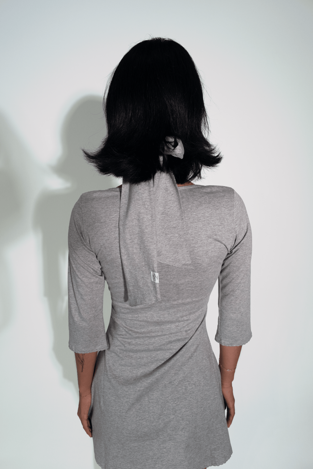 Person wearing a gray dress with a plain background