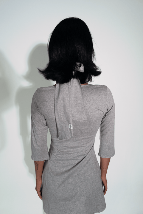 Person wearing a gray dress with a plain background