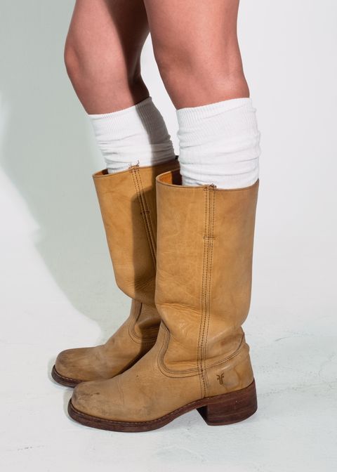 Tan knee-high boots worn with white socks on a plain background