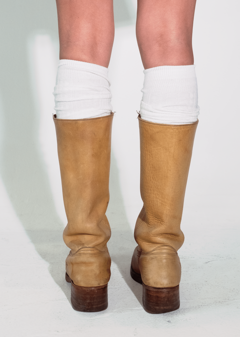 Tan knee-high boots with white socks on a plain background